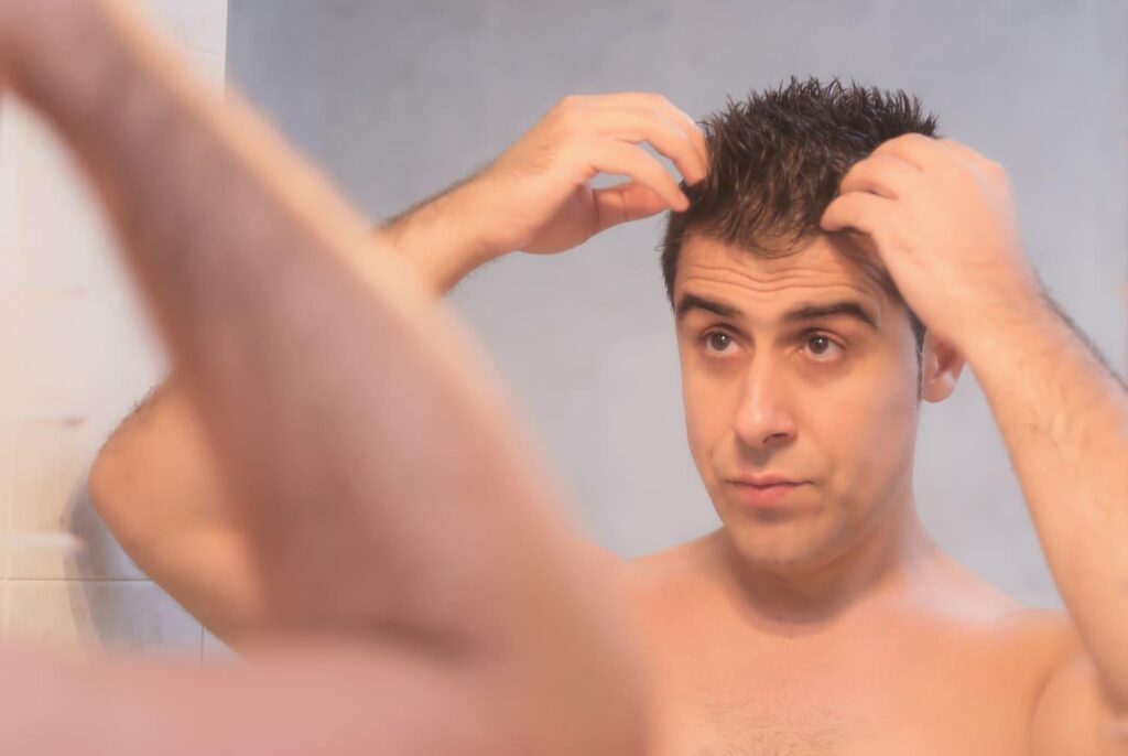 Man inspecting hair regrowth in the mirror months after a hair transplant