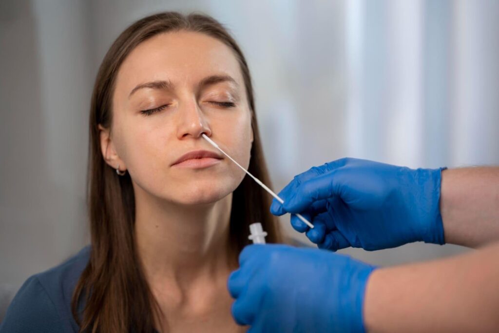 Clinician in blue gloves examining a patient's nose during a rhinoplasty consultation
