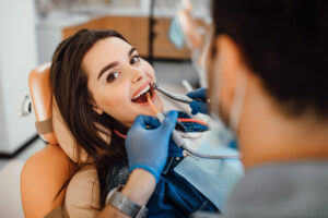 Dentist examining a smiling female patient in a dental chair