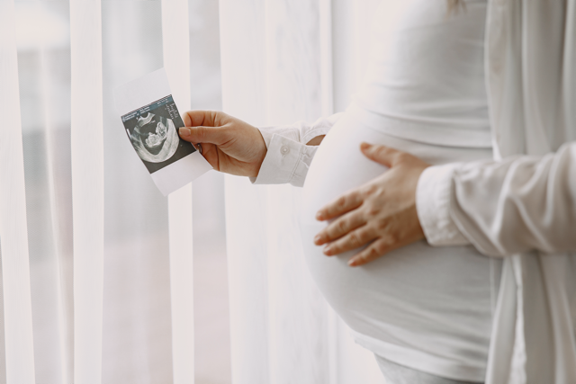 pregnant woman holding a photo of her baby